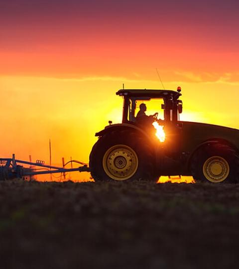 Silhouet van tractor bij zonsondergang, met tekst “Verdant les semis”